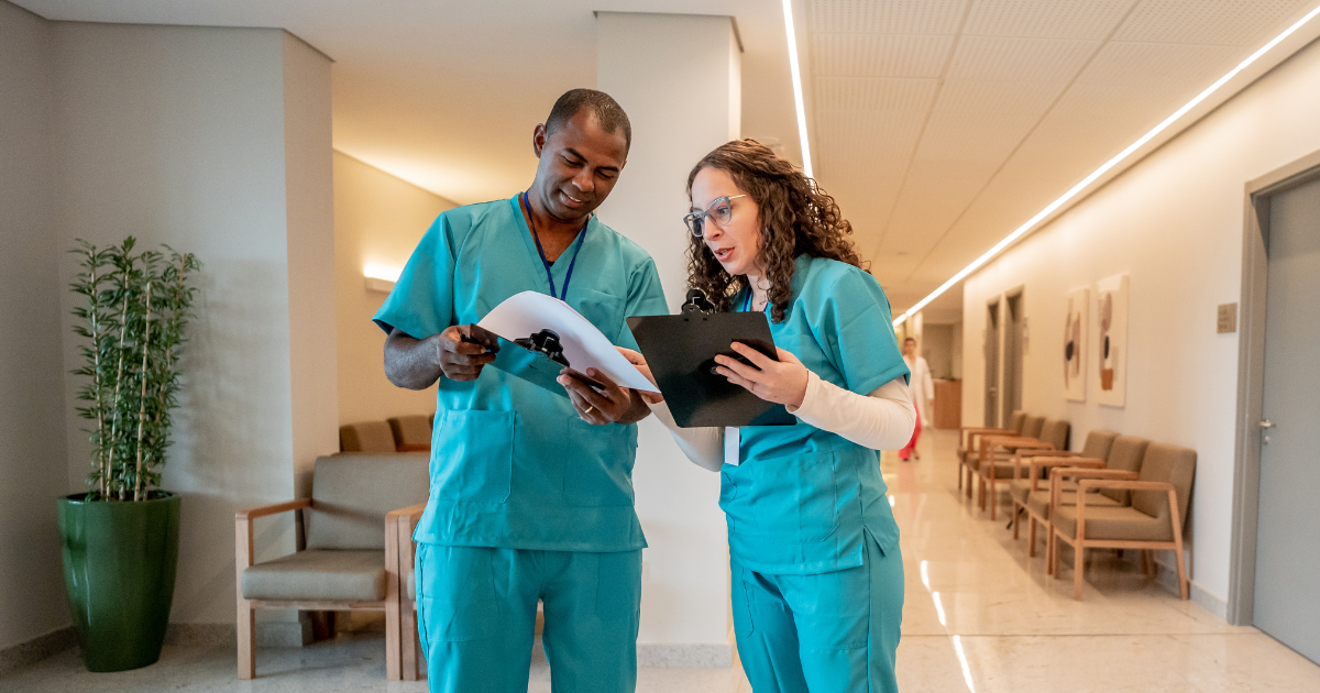 Two nurses reviewing patient charts in a hallway, highlighting collaboration and daily contributions recognized during Nurses Week.