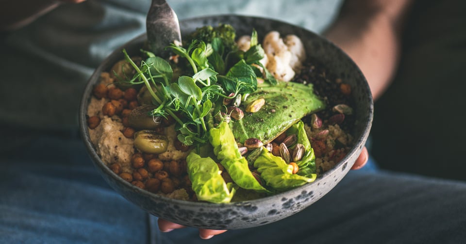 A close-up of a person holding a bowl filled with vegetables and grains, supporting nutrition and wellness in addiction recovery.