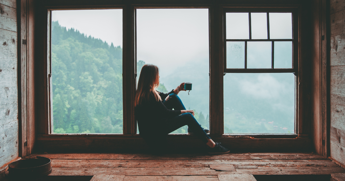A person sitting by a window with coffee, symbolizing mindfulness and emotional awareness - key coping skills in recognizing early signs of cravings during recovery.