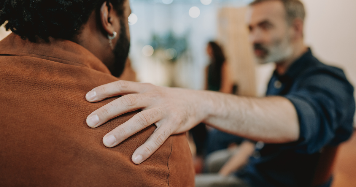 Peer support in recovery, showing one person offering comfort to another, symbolizing collaboration in addiction treatment.