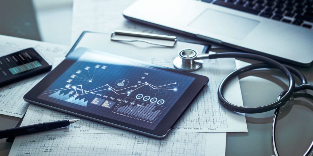 Healthcare professional's desk with stethoscope, tablet displaying medical analytics, and patient data charts.