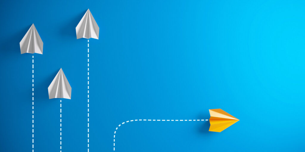 Gold paper airplane breaking away from group of white planes, symbolizing leadership and innovation in addiction recovery.