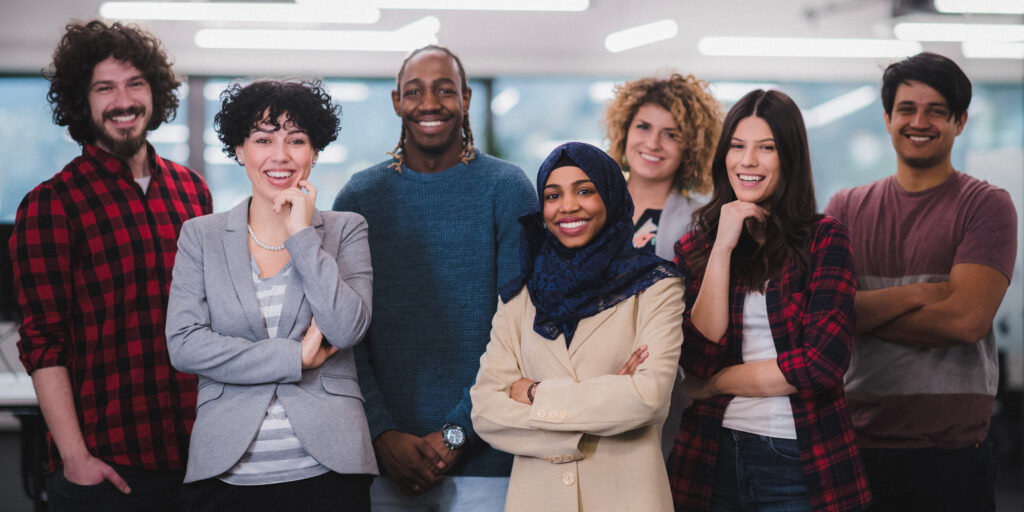 Diverse team of seven smiling professionals standing together during Corporate Compliance and Ethics Week event.