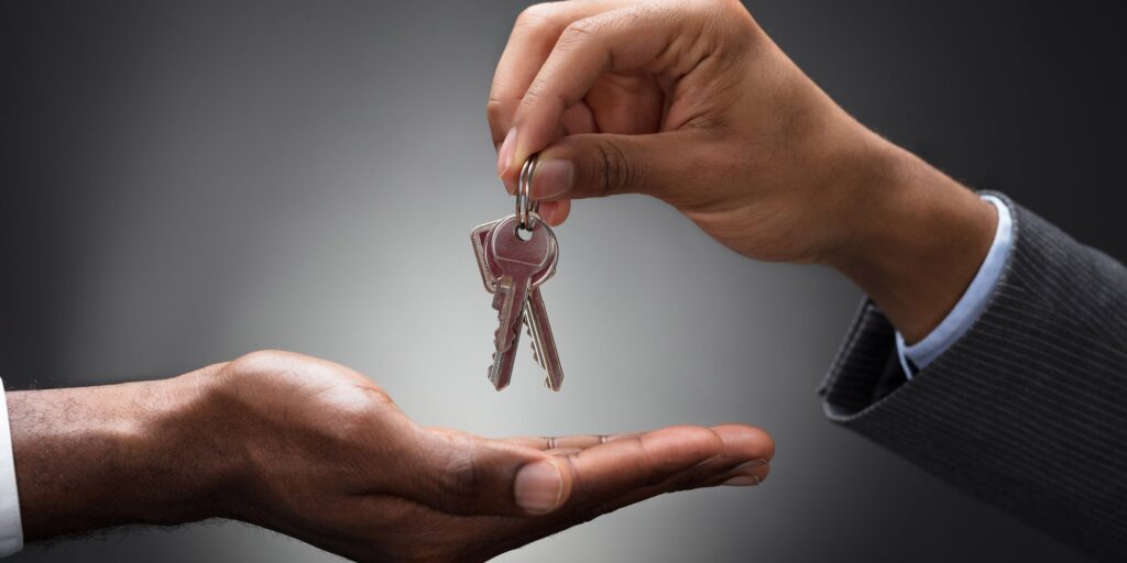 Real estate agent handing house keys to new homeowner in professional transaction.