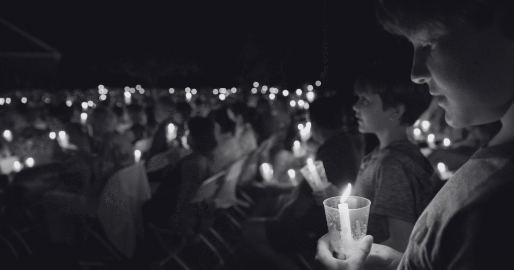 A large group gathering holding candle lights, symbolizing remembrance for those who died from drug and alcohol misuse on International Overdose Awareness Day.