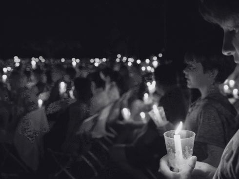 A large group gathering holding candle lights, symbolizing remembrance for those who died from drug and alcohol misuse on International Overdose Awareness Day.