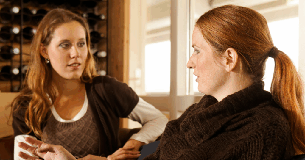Two women having a serious conversation in a home setting discussing recovery strategies.