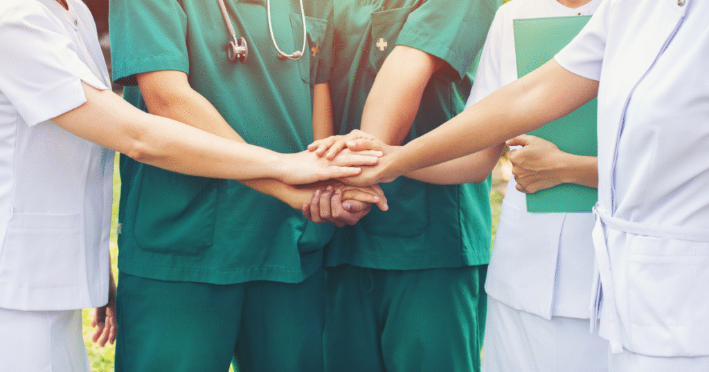 A team of nurses and other medical staff joining hands in honor of Nurses Week.
