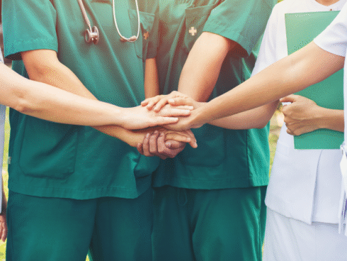A team of nurses and other medical staff joining hands in honor of Nurses Week.