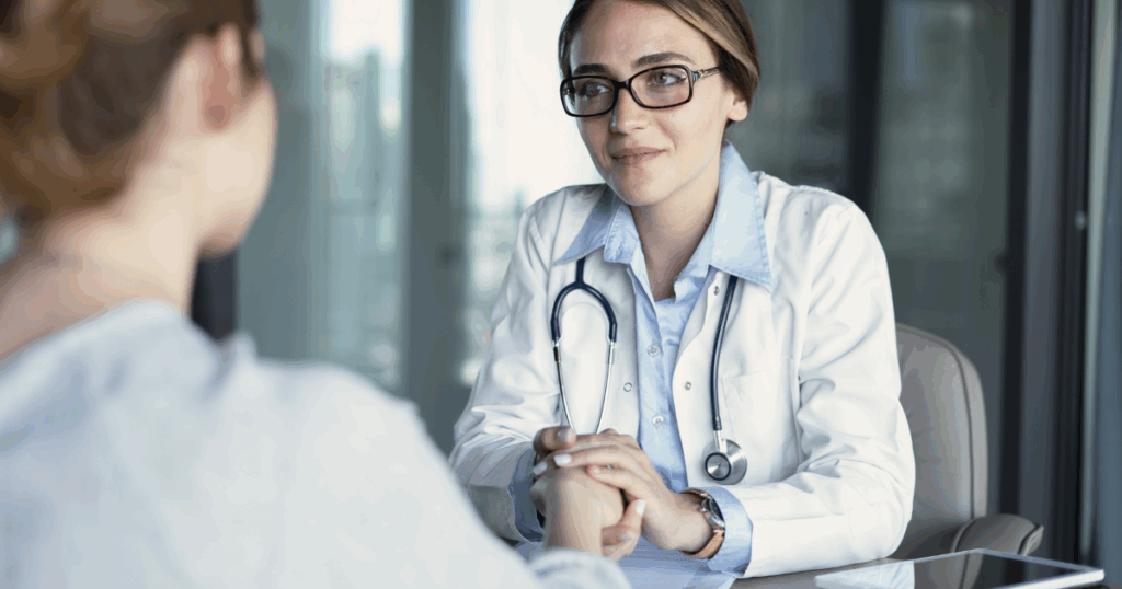 Doctor gently holding a patient's hand, offering reassurance and emotional support during a discussion about recovery.
