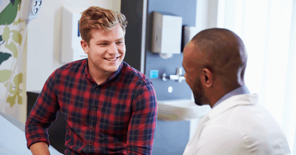 Young man in plaid shirt smiling while discussing naltrexone treatment with healthcare provider.