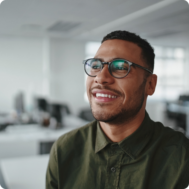 Smiling man wearing glasses in modern office setting, representing BHG Health addiction recovery services.