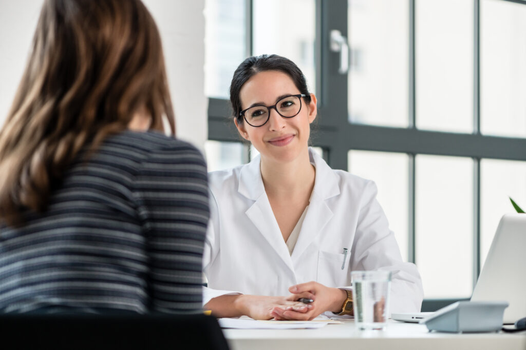 Female physician or medical director listening to her patient during an intake process for substance use disorder treatment while sitting down in an private office.