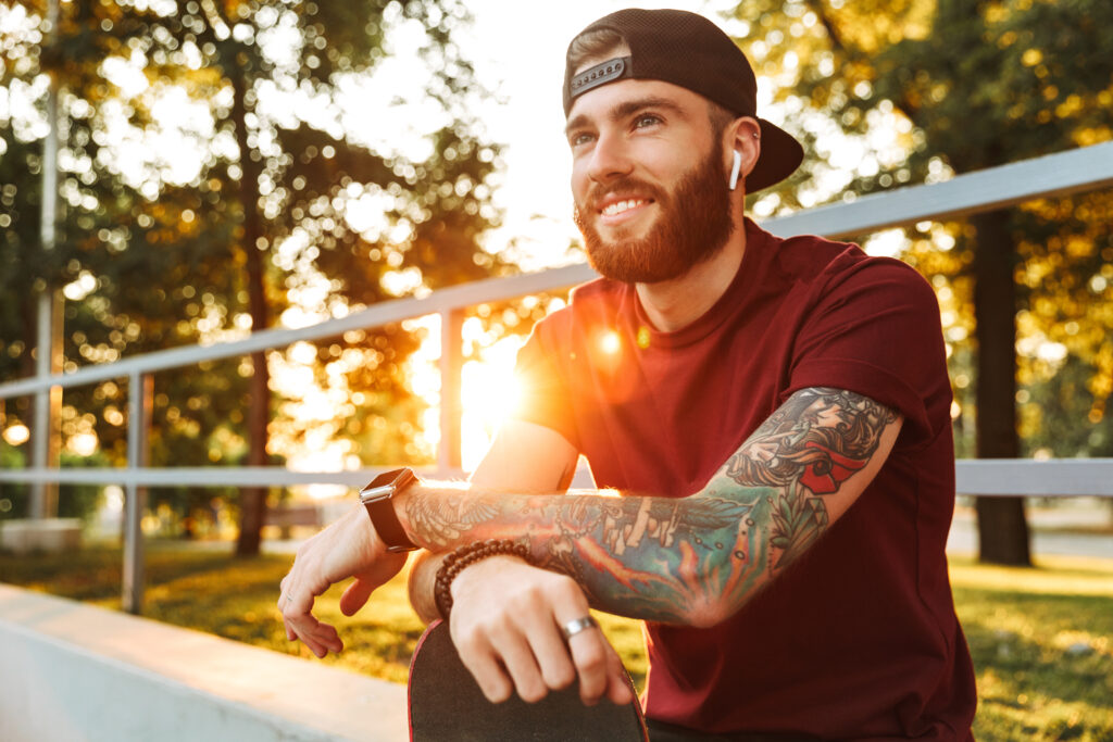 Attractive cheerful young man sitting at a park, symbolizing hope in addiction recovery for substance use disorder.