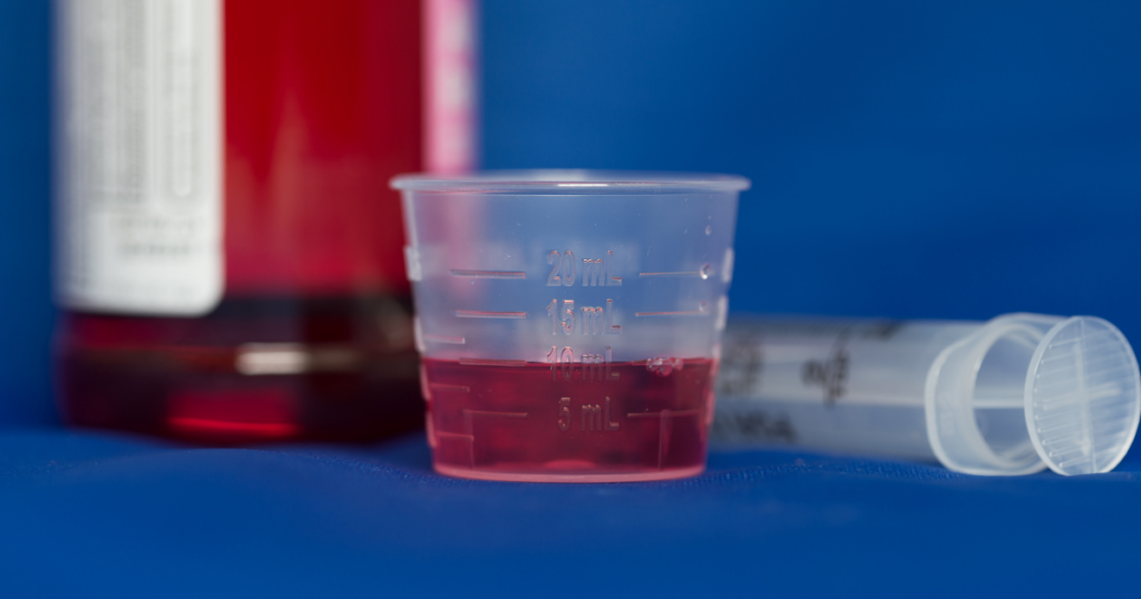 Liquid methadone dose prepared in a measuring cup for supervised opioid treatment program dosing.