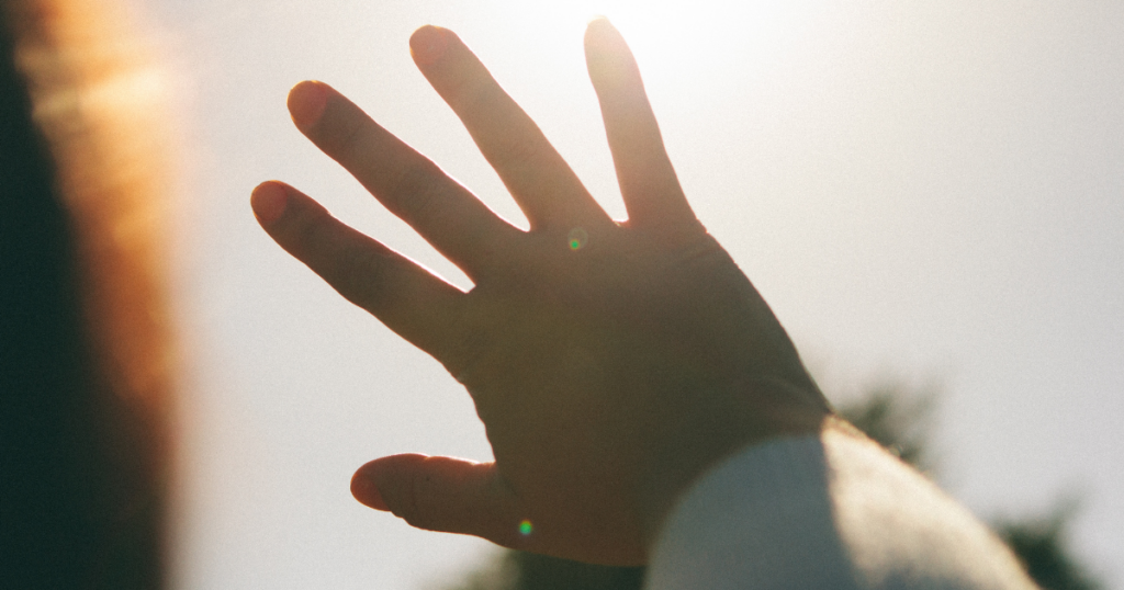 Hand shielding bright sunlight to illustrate the importance of sun protection.