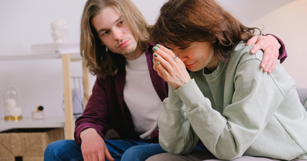 Person comforting a grieving loved one, illustrating coping with grief during addiction recovery.