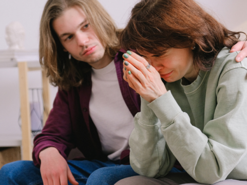 Person comforting a grieving loved one, illustrating coping with grief during addiction recovery.