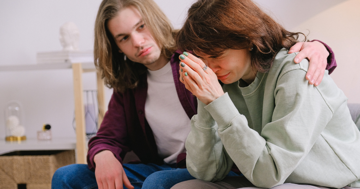 Person comforting a grieving loved one, illustrating coping with grief during addiction recovery.