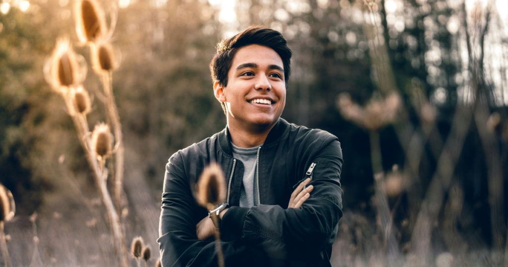 Young man in recovery after treatment for co-occurring disorders, smiling outdoors with confidence.